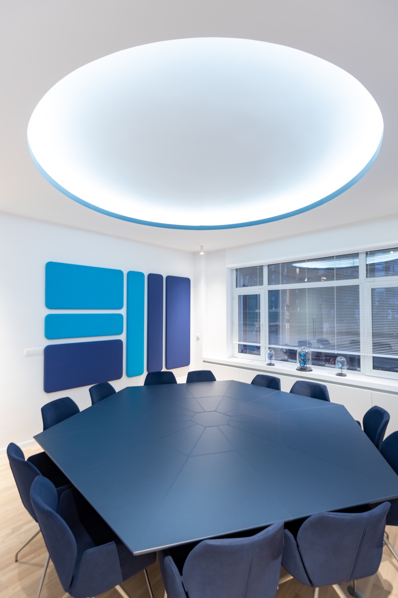 Salle du conseil hexagonale bleu nuit sous oculus lumineux, aménagée par BE-DESIGNER