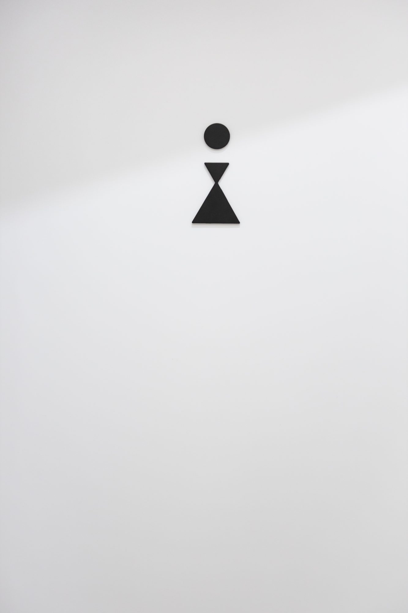Brugmann 421 — Signalétique — pictogramme en métal noir sur mur blanc immaculé